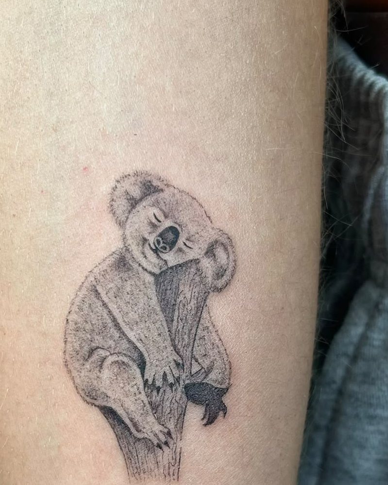 Koala de microrealismo agarrado a una rama en el brazo