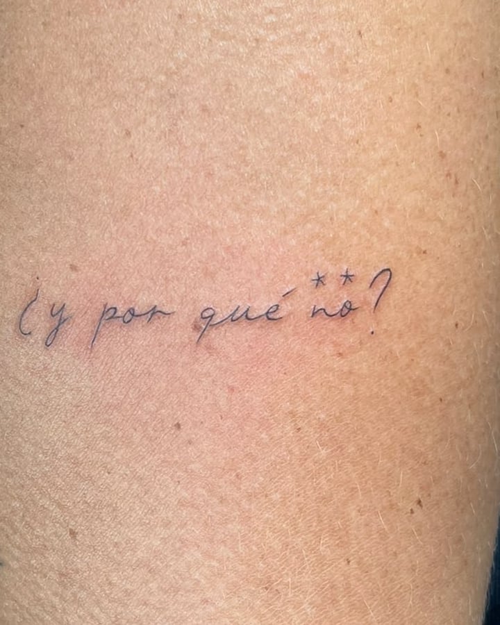 Frase «¿y por qué no?» en letra manuscrita fina en el brazo