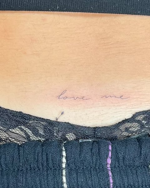 Frase «love me» en letra fina en la zona lumbar